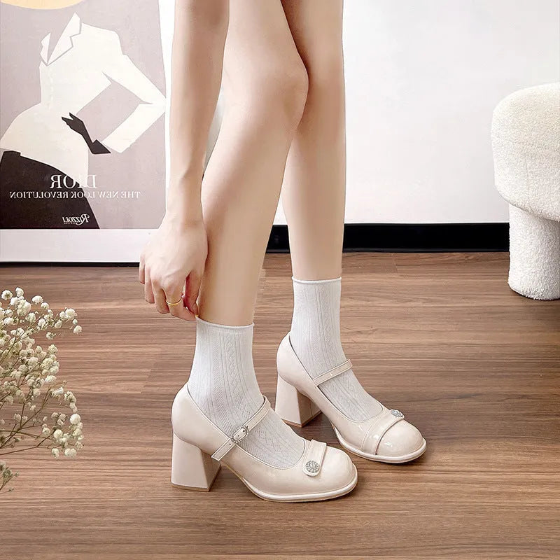 Women's black patent leather chunky heel court shoes with round toe and buckle fastening.