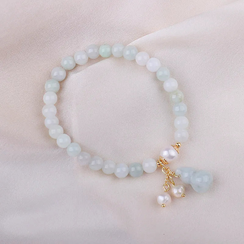 Women's handmade jade bracelet with traditional gourd charm design and pearl accents in natural emerald green colour