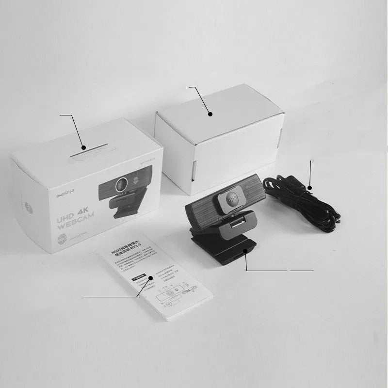 Black USB webcam with magnetic privacy cover on a desktop next to a laptop.
