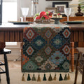 Dark blue jacquard table runner with bouquet pattern and tassels laid on a wooden dining table.