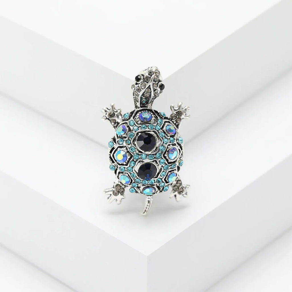Close-up of a retro-style rhinestone turtle brooch in alloy, shown in blue, green and red colour options.