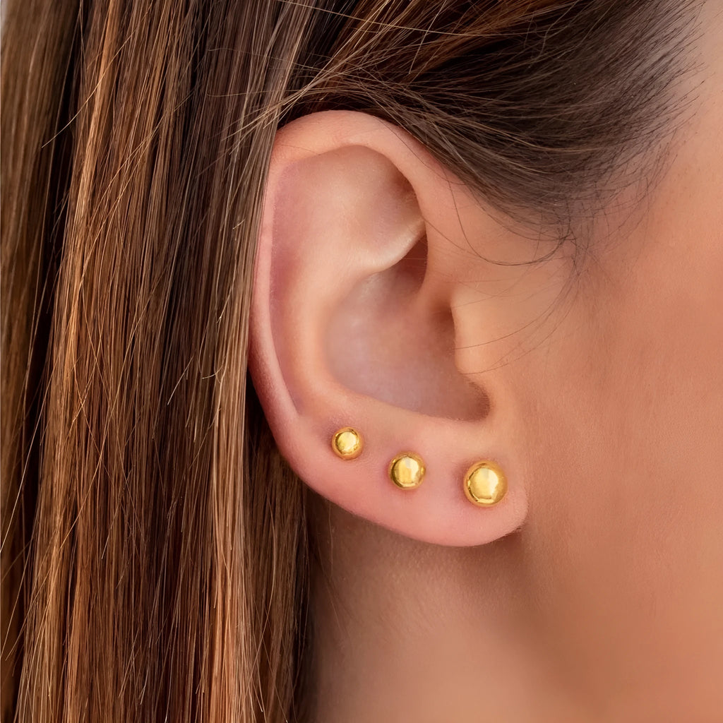 Stainless steel minimalist ball stud earrings with a round geometric shape, shown in various sizes.