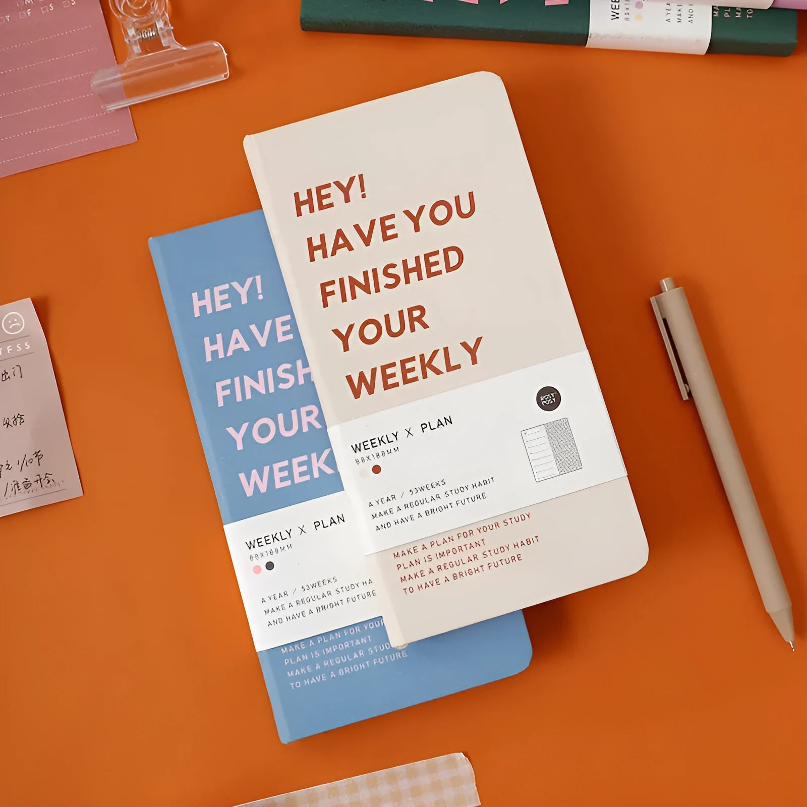 A5 weekly plan diary handbook open on a desk, showing weekly layout, with blue, brown, green, and purple cover options.