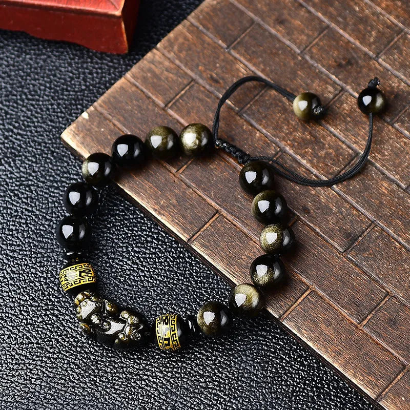 Hand-woven golden obsidian Pi Xiu bracelet with animal zodiac charm on wrist.