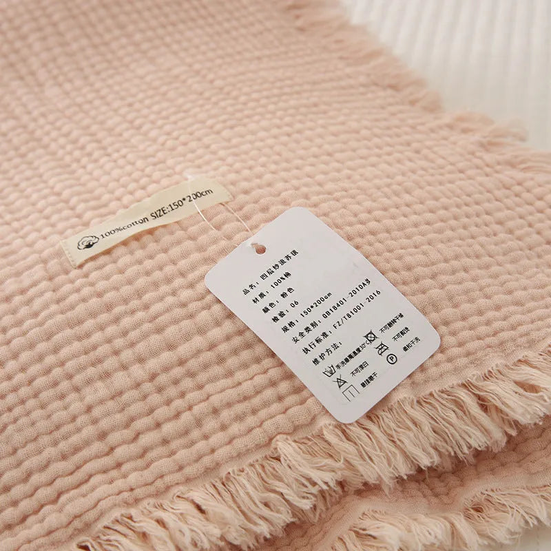 Four-layer gauze cotton blanket with tassel trim in avocado green, laid flat.