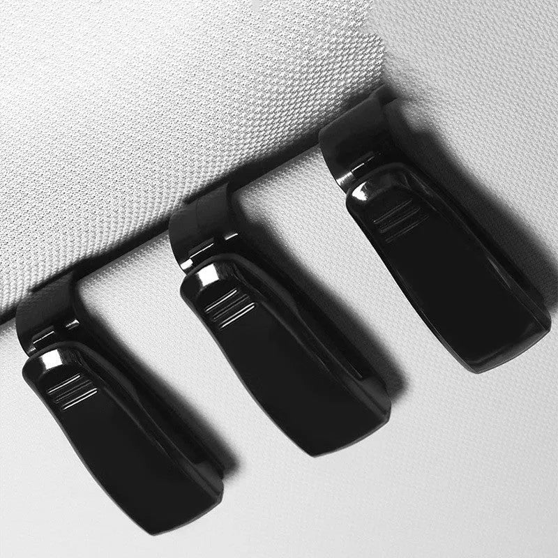 Black plastic multifunctional clip for car sunshades, holding sunglasses and a card.