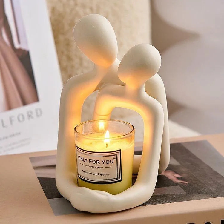 A milky white resin statue of a loving couple, modern home decor accent on a wooden shelf.