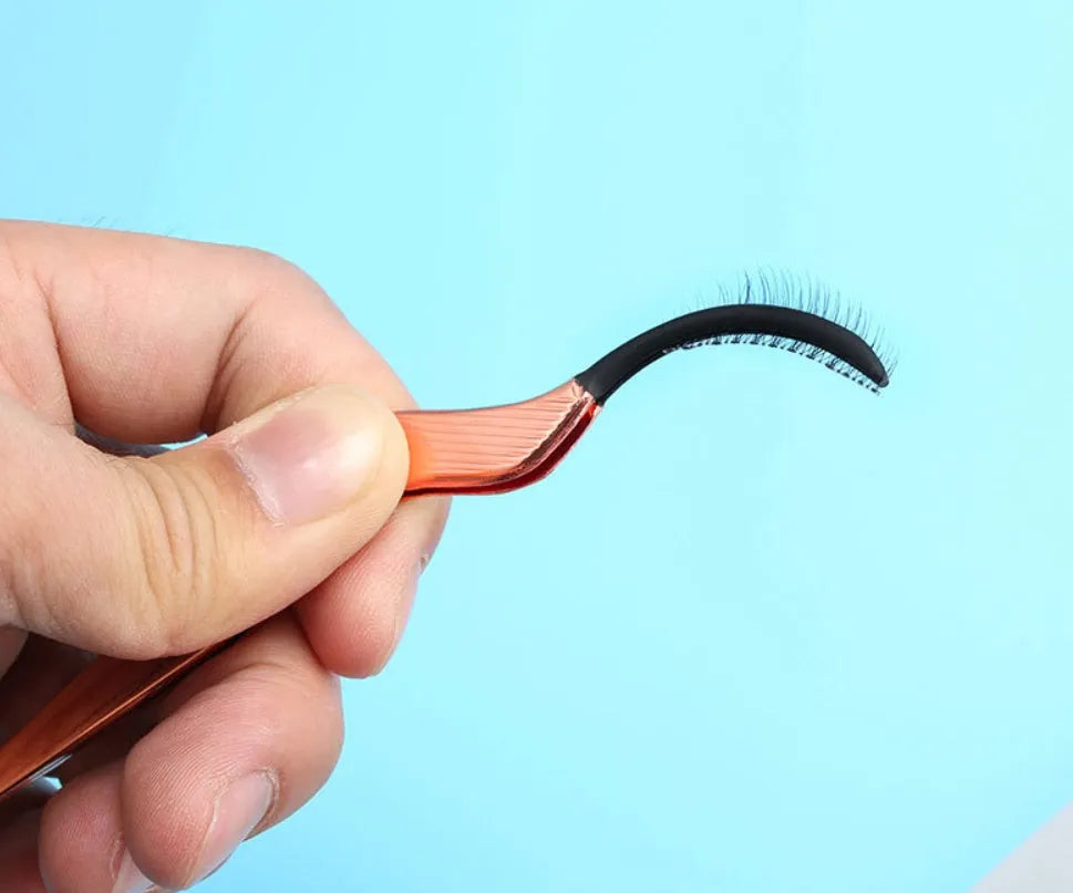 Rose gold metal false eyelash curler aid tool on plain background