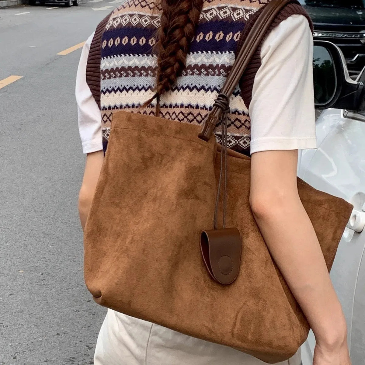 Brown suede shoulder bag with double straps and sewing line detail on a white background