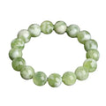Polished green milk-in-water Xiuyan jade bracelet showing single circle of beads on a wrist.