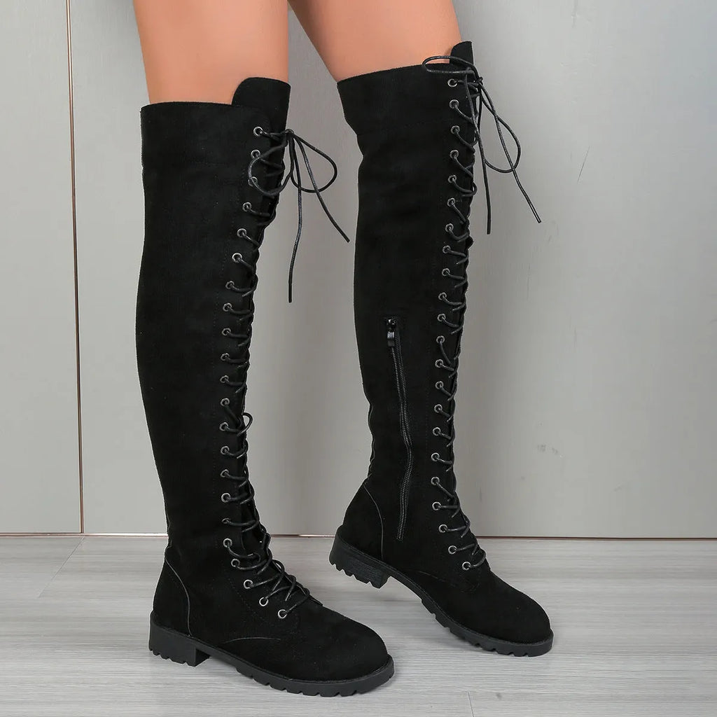 Black lace-up over-the-knee boots with a round head and flat rubber sole on a neutral background.