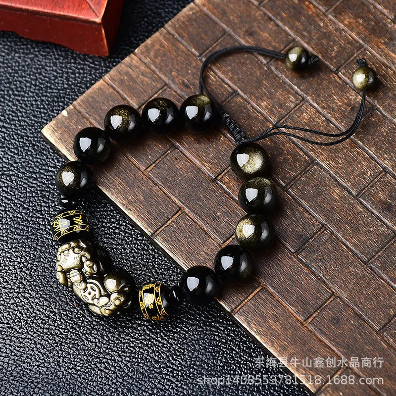 Hand-woven golden obsidian Pi Xiu bracelet with animal zodiac charm on wrist.