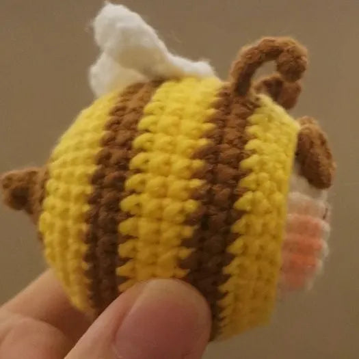 Handmade crocheted plush bee hive and bees accessory for woolen dolls on a white background.