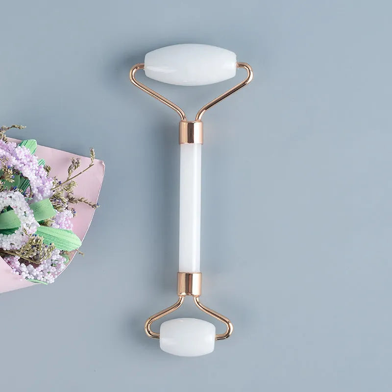 White jade facial roller set with double-headed roller claw and scraping board on wooden surface