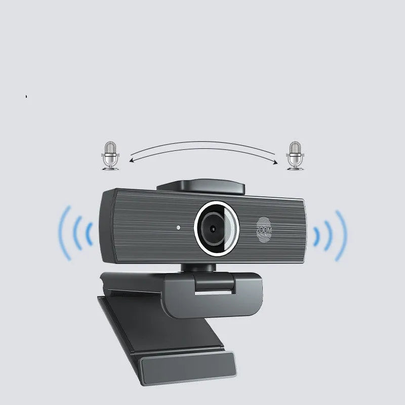 Black USB webcam with magnetic privacy cover on a desktop next to a laptop.