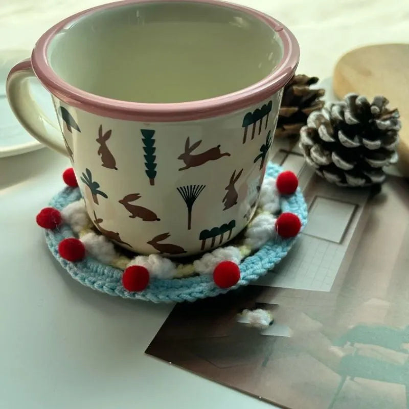 A single 9cm round wool coaster and its decorative cake-themed storage bag.