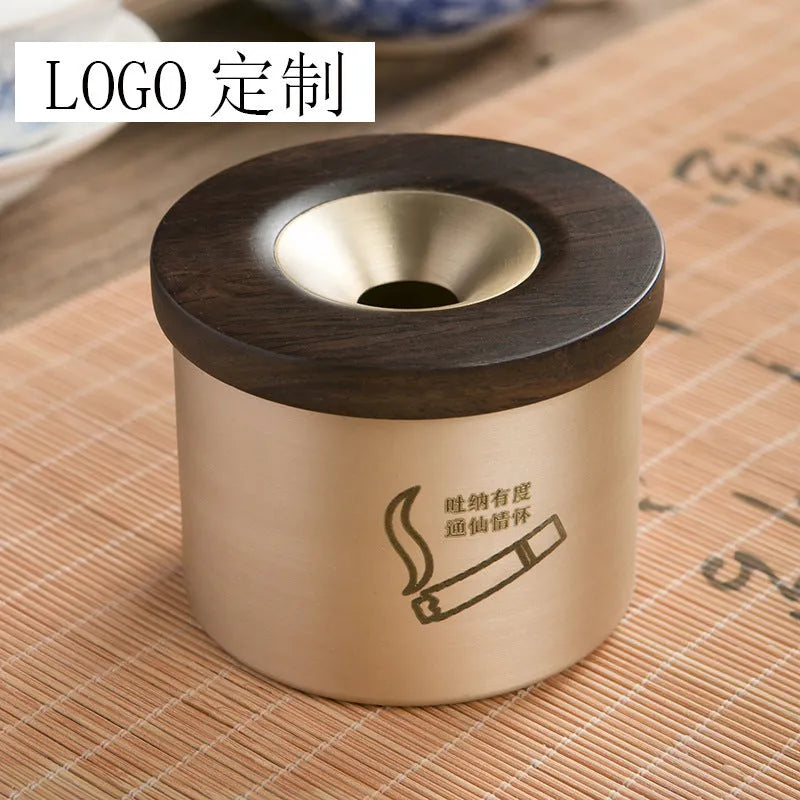 Brass-coloured copper ashtray with a wooden lid on a tabletop.