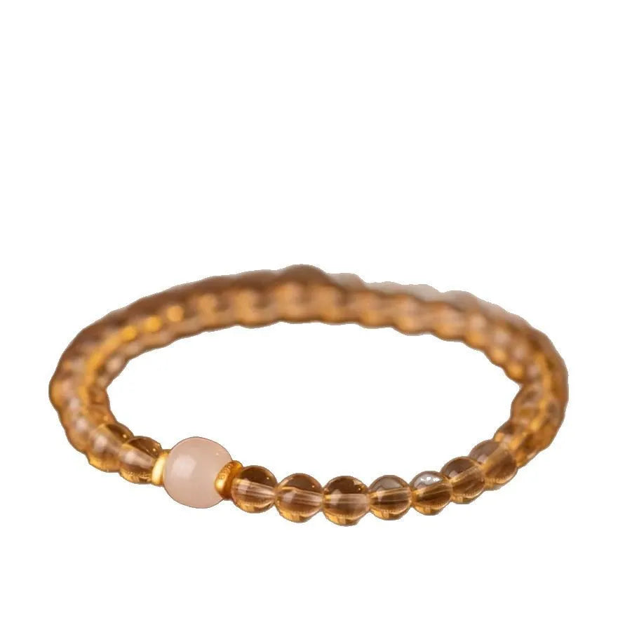 Close-up of a handmade adjustable bracelet made from natural rutilated quartz beads with golden rutile needle inclusions.