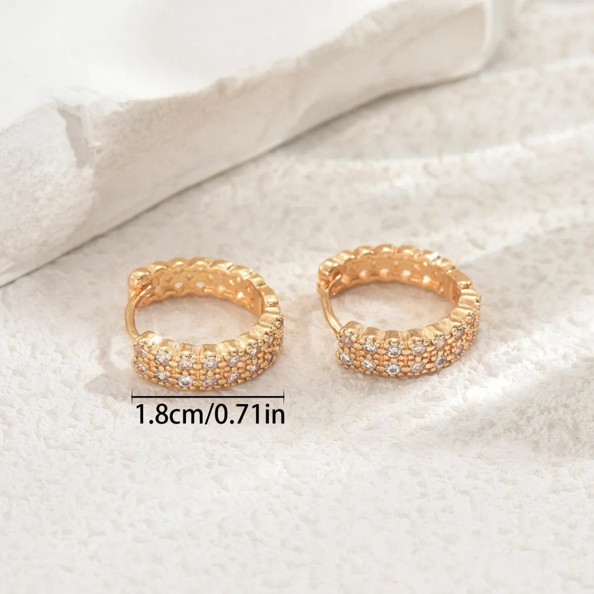 A pair of geometric pattern copper ear studs with round, dot, and ring decorative details.