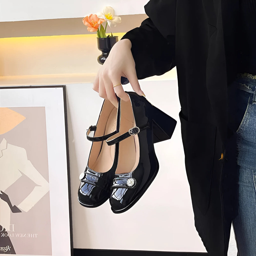 Women's black patent leather chunky heel court shoes with round toe and buckle fastening.