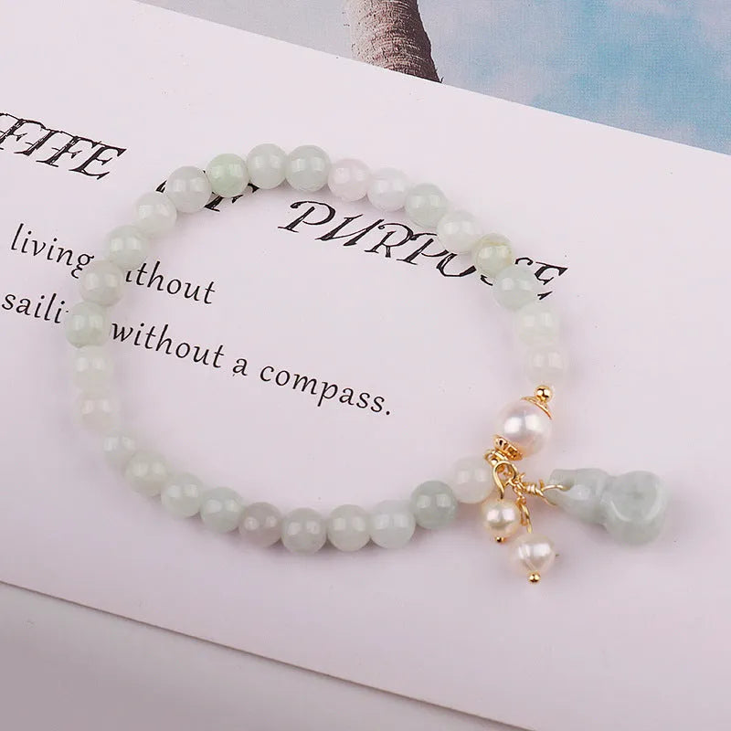 Women's handmade jade bracelet with traditional gourd charm design and pearl accents in natural emerald green colour