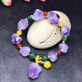 Purple amethyst bracelet with natural shaped beads and a fu character charm on a white background.