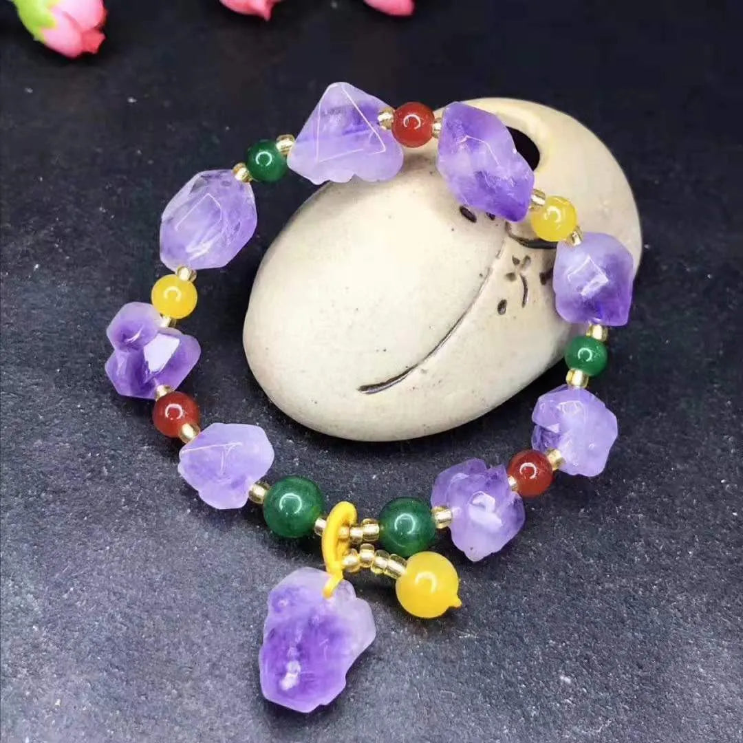 Purple amethyst bracelet with natural shaped beads and a fu character charm on a white background.