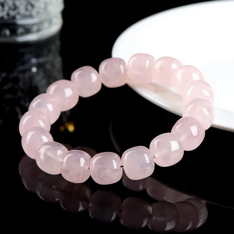 Close-up of a pink crystal bracelet with barrel-shaped beads on a wrist.