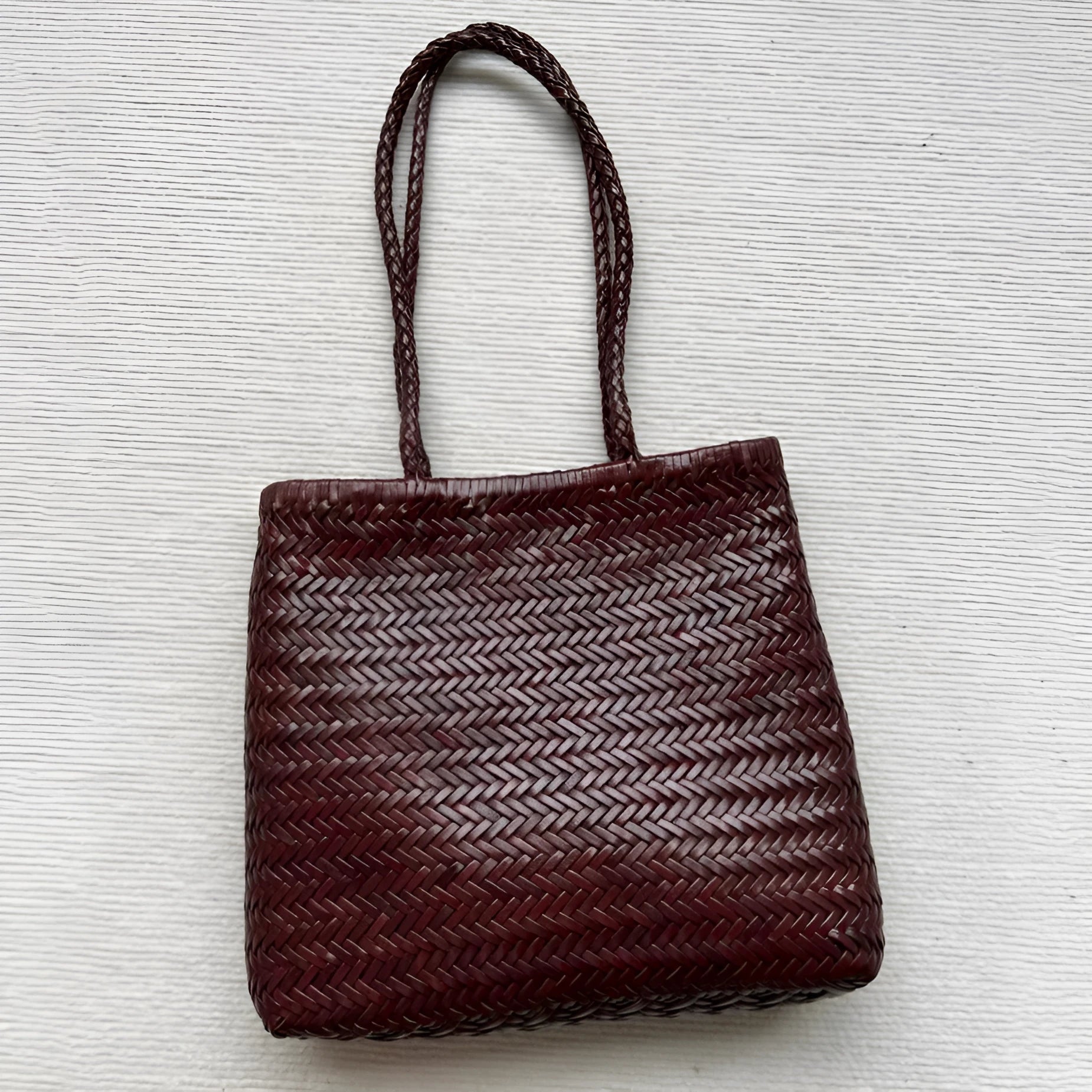 Brown handmade woven leather tote bag with a three-dimensional front pocket.