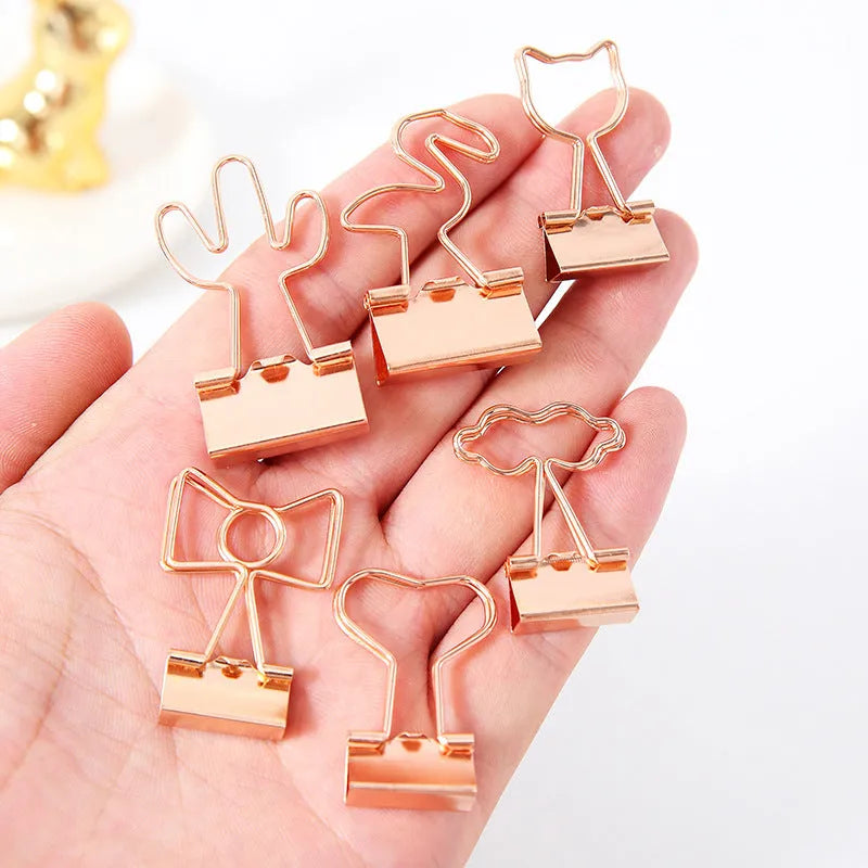 Small gold metal office clip with long tail, showing flamingo, love, cloud, cat, cactus, and bow shape options.