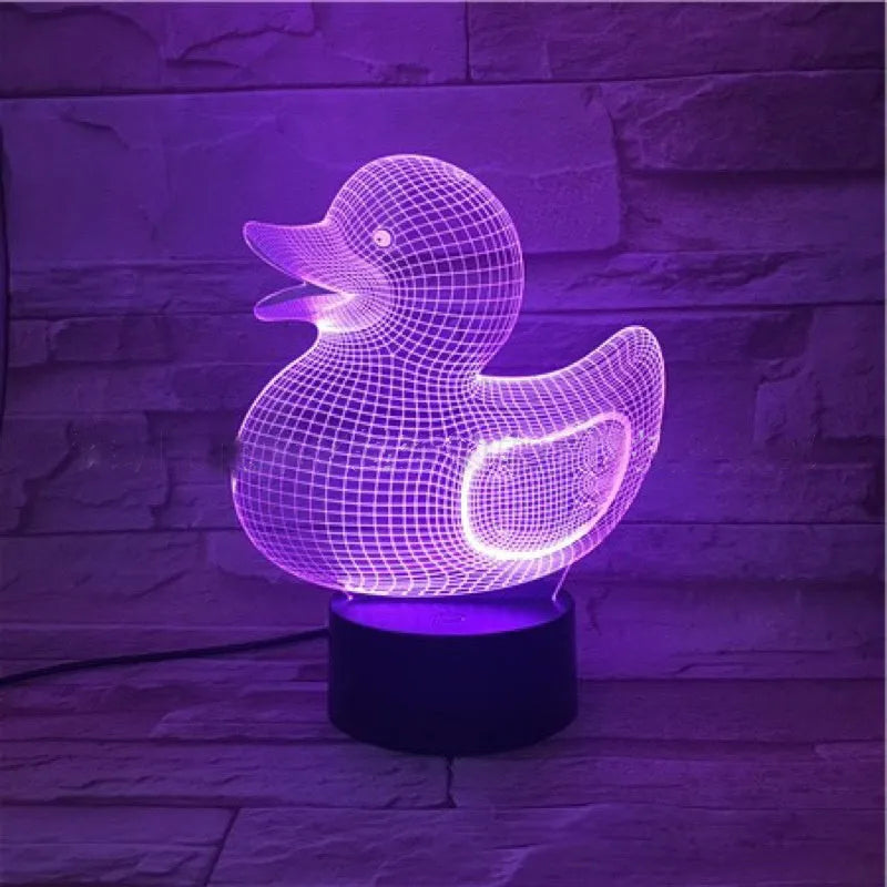 Little yellow duck 3D night light showing colourful LED illumination on a table with remote control.