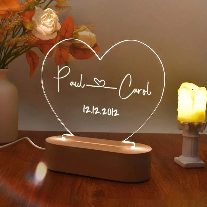 Custom transparent acrylic night light with personalised text, lit by LED, on a bedside table.