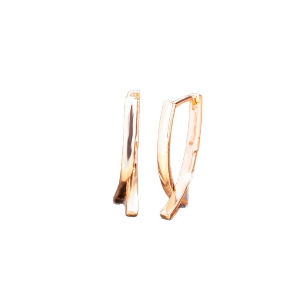 Rose gold coloured cross shaped earrings made from copper metal on a white background.