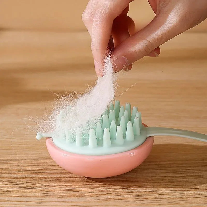 A blue silicone pet bathing brush with soft bristles and a palm-grip base for washing dogs and cats.