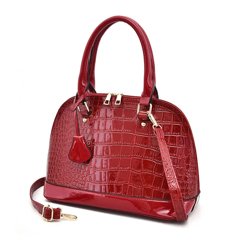 Large shiny black PU leather crossbody bag with shell suitcase shape on a model