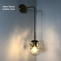 Modern simple glass bedside wall lamp in silver or gold finish on a white wall.