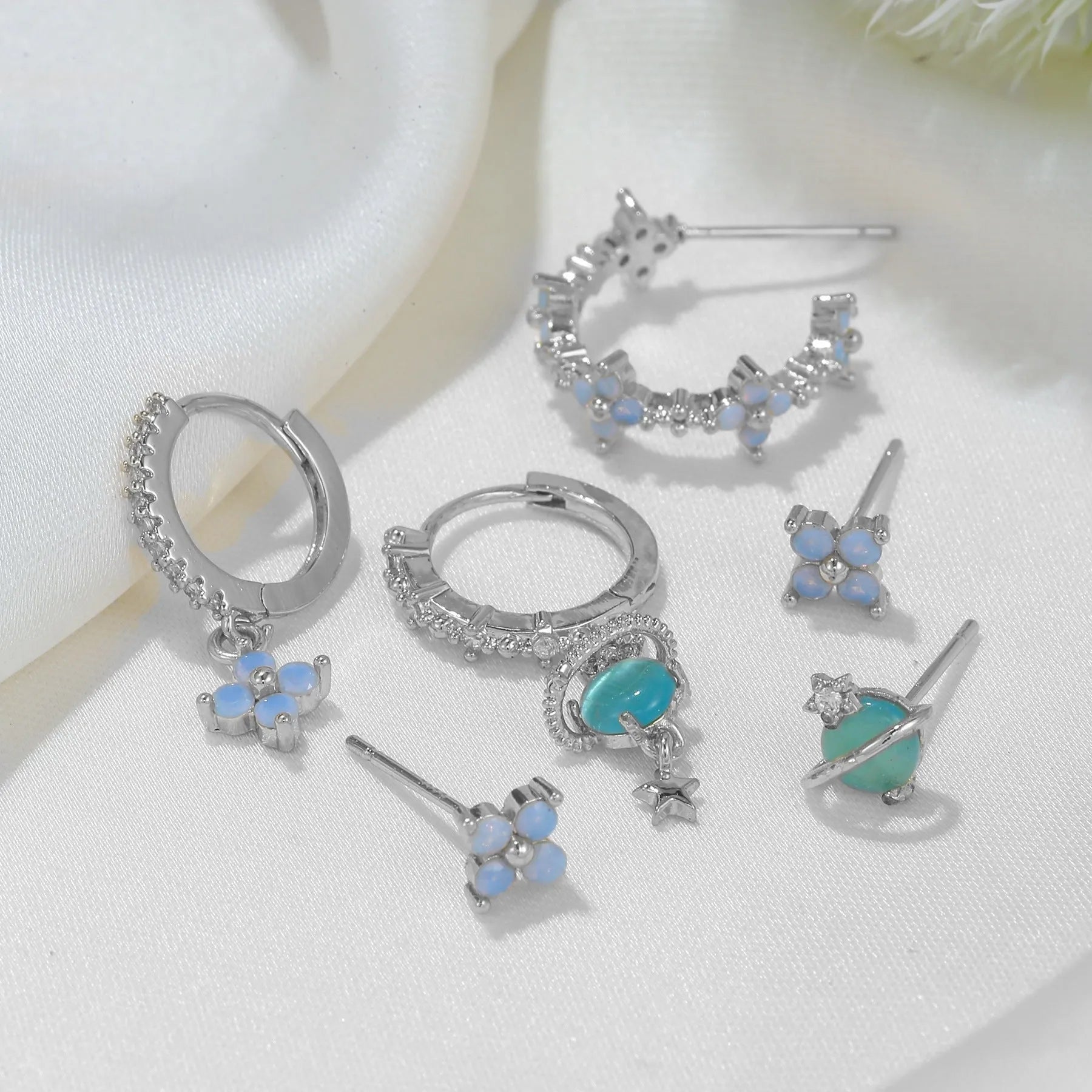 Gold and silver flower shaped stud earrings with a central zircon stone, showing front and back.