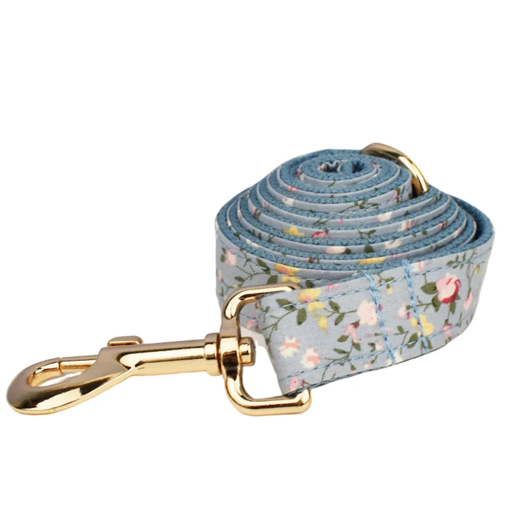 Blue floral cloth dog collar and leash set with bow and vest accessories on a size chart from XS to XL.