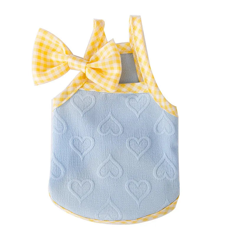 Small dog wearing a blue heart relief texture vest with bow suspenders and a matching hairband.