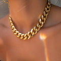 Women's gold tone thick chain necklace with a pendant on a white background.