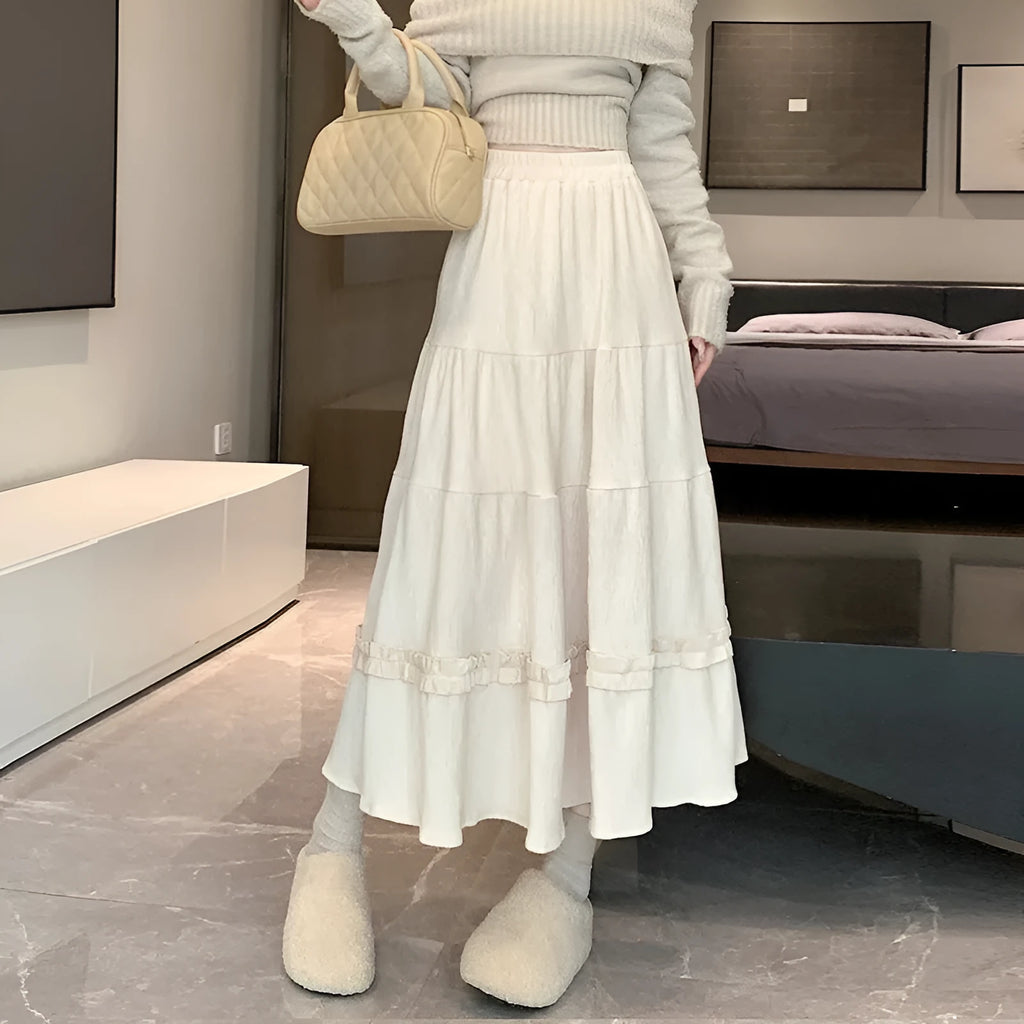 A slimming milky white corduroy A-line midi skirt with an elastic waistband laid flat.