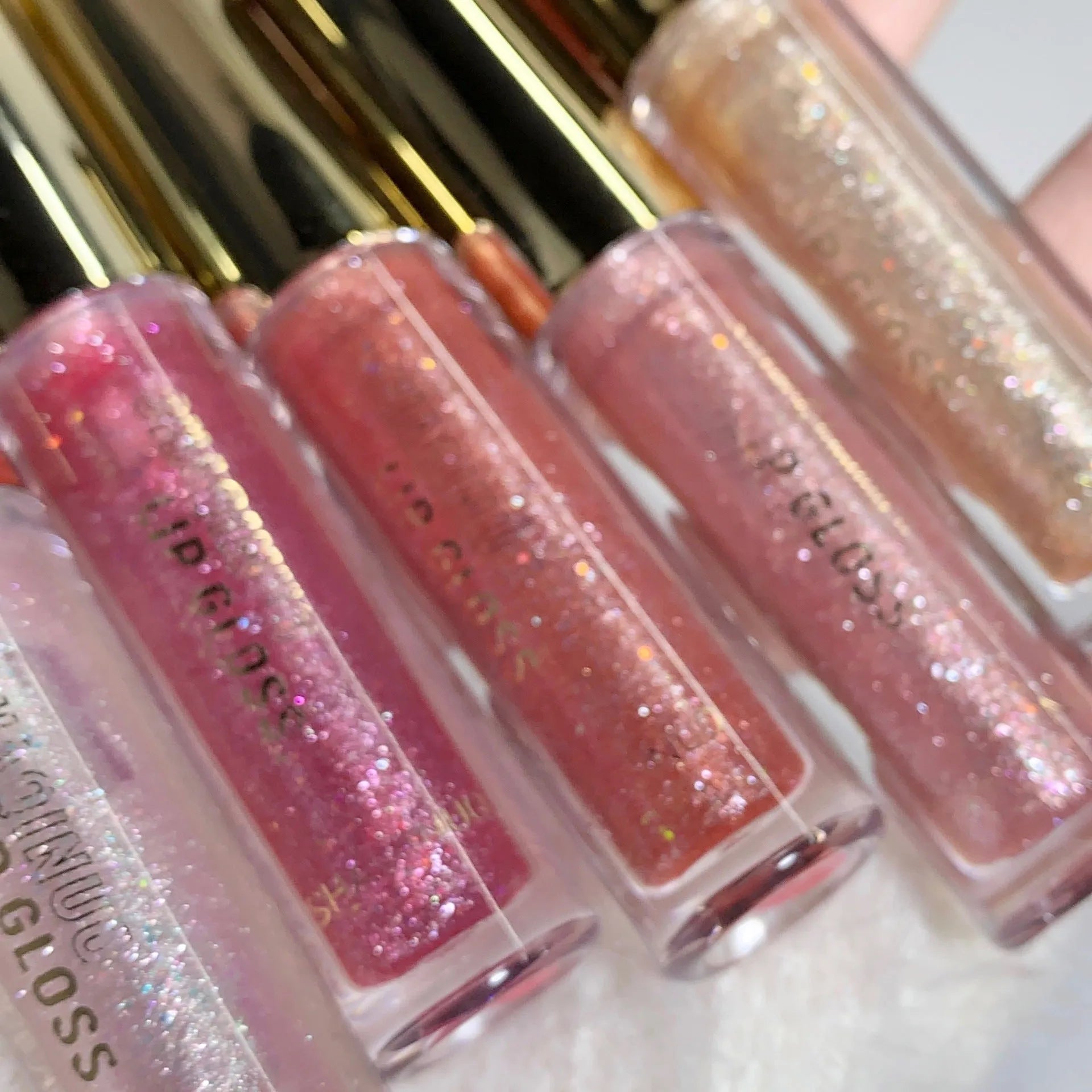 Shanuo Flash Lip Gloss tube showing five colour shades: cherry blossom pink, gold flash, peach, purple, and berry red.