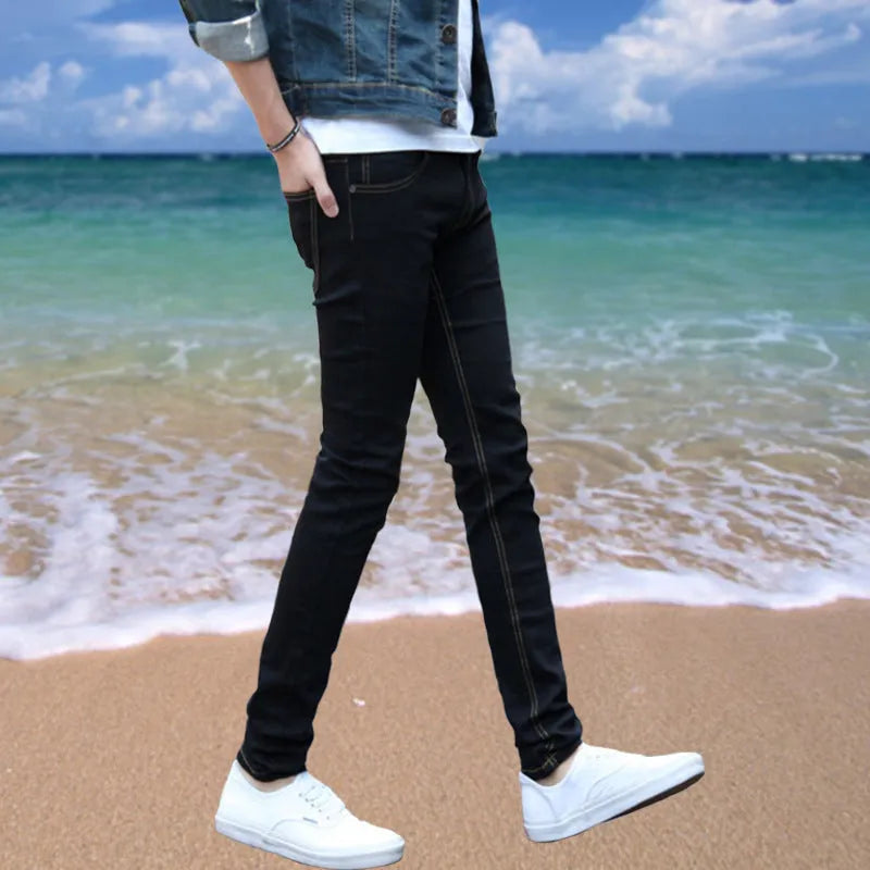 Thin men's loose skinny casual jeans in pure black with low waist, cropped leg, small leg opening, and zip fly.