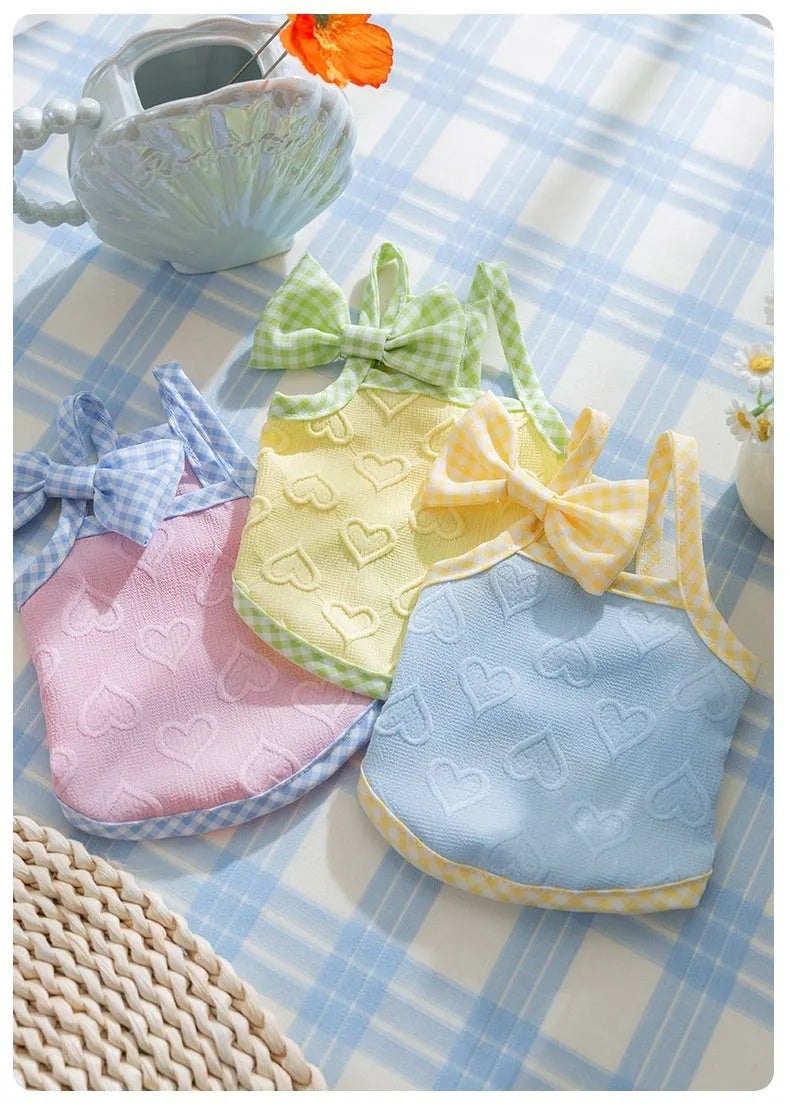 Small dog wearing a blue heart relief texture vest with bow suspenders and a matching hairband.