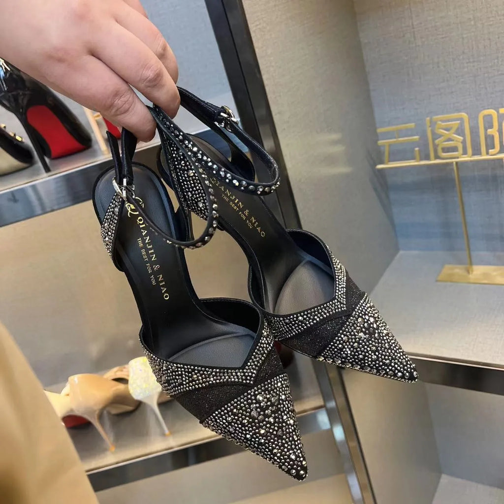 Women's black high-heeled shoes with a red sole, showing stiletto heel and pointed toe design.