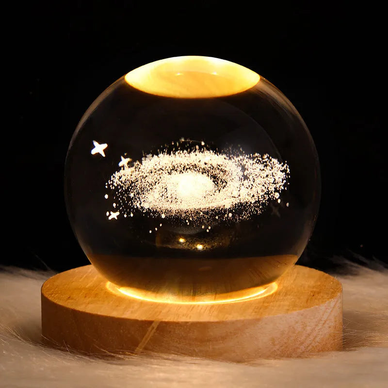 LED galaxy crystal ball night light with 3D planet designs on a table