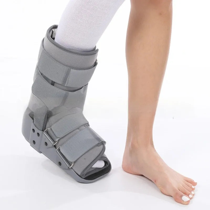 Black Achilles tendon rehabilitation boot with aluminium uprights on a grey background.