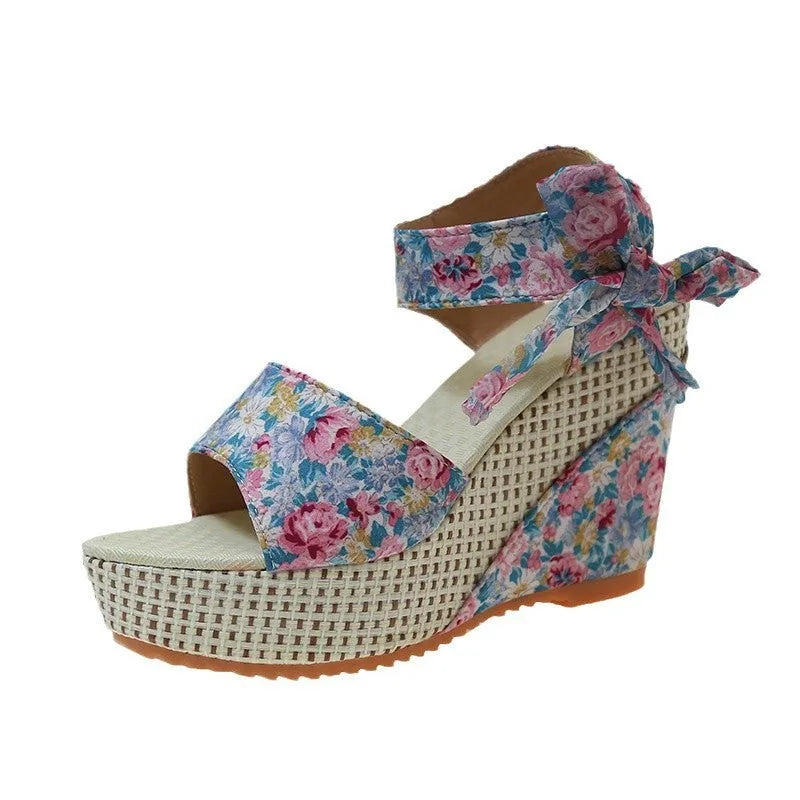 Women's pink floral peep toe wedge sandals with an ankle strap buckle on a rubber sole.