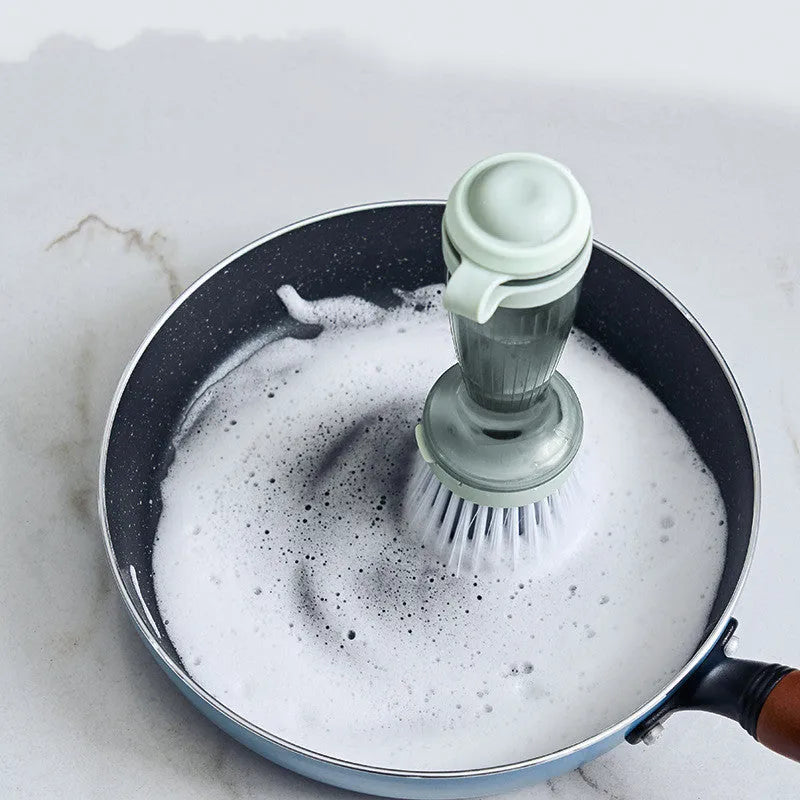 Milk white pot brush with soap dispenser in handle and non-scratch bristles for kitchen sink use.