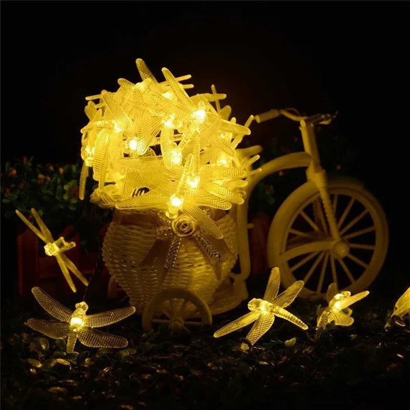 Five-metre solar-powered outdoor string lights with 30 warm white dragonfly-shaped LEDs and a separate solar panel on a spike.